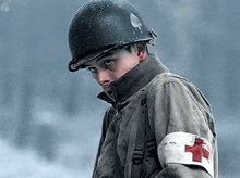 a soldier with a red cross on his arm is wearing a helmet .