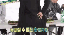 a woman in a black dress is standing in front of a table with a green bottle of water .