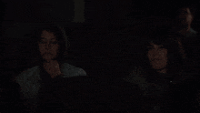 two people are watching a movie in a dark theater .