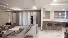 a woman is walking through a living room with the words made in animatica on the bottom right