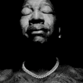 a black and white photo of a man with his hands folded in prayer .
