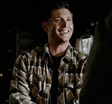 a man in a plaid shirt talking to another man