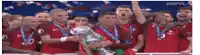 a group of soccer players are holding a trophy and celebrating their victory .