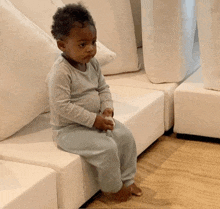 a little boy is sitting on a white couch holding a toy
