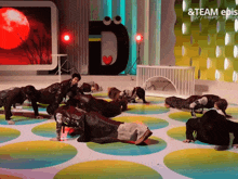 a group of people are doing push ups in front of a large letter d on a stage