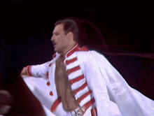 a man in a white and red striped jacket is dancing on stage .