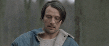 a man in a denim jacket is holding a gun in his right hand