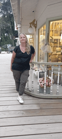 a woman standing on a porch with flowers in front of her