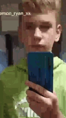 a young boy is taking a selfie with his cell phone ..