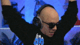 a bald man wearing headphones and sunglasses is dancing .