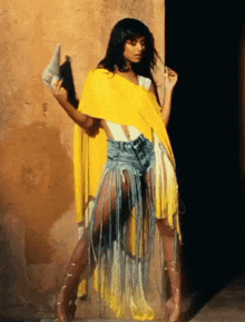 a woman wearing a yellow fringed skirt and shorts