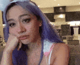 a woman with purple hair wearing bunny ears looks at the camera