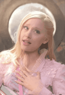 a blonde woman in a pink dress is holding a book