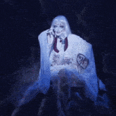 a woman in a white dress is sitting in a dark room