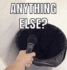 a person is holding a microphone in front of a trash can with the words `` anything else ? '' written on it .