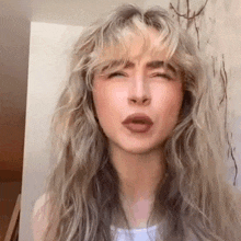 a woman with long blonde hair and bangs is making a face .