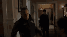a man in a sheriff 's uniform is standing in a living room next to a man in a black coat .