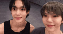 two young men are posing for a picture and one has a cross necklace around his neck