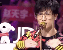 a man wearing glasses is singing into a microphone with a sign in the background that says jd