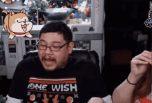 a man wearing glasses and a one wish shirt is sitting in a chair
