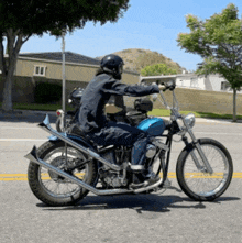 a man wearing a helmet is riding a blue motorcycle down a street