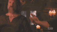 a man with a beard is holding another man 's hand with a cw logo visible in the background