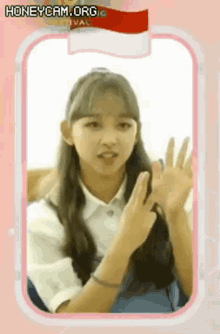 a young girl is giving a peace sign in front of a flag .