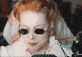 a woman wearing sunglasses and headphones is looking at a computer screen .