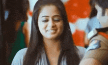 a woman is smiling and looking at the camera while a man stands behind her .