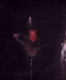 a woman with red hair is singing into a microphone on stage