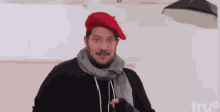 a man is wearing a red beret and a scarf .