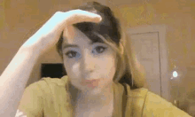 a young woman is holding her hand to her forehead .