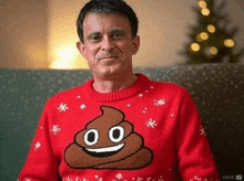a man wearing a red sweater with a poop face on it .