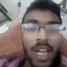 a man with glasses and a beard is talking on a phone .