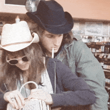 a man in a cowboy hat is smoking a cigarette next to a woman
