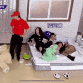 a man in a red shirt stands next to a group of people laying on a bed with a sign that says eye