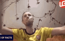 a man in a yellow adidas shirt is sitting on a couch