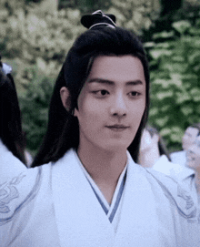 a man with long black hair is wearing a white shirt