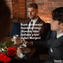 a man in a suit sits at a table with two other men and a red rose