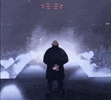 a bald man in a black coat is standing on a stage