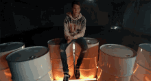 a young man sits on a barrel with a hoodie that says ' rock n ' roll ' on it