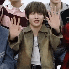 a young man is waving his hands in the air while standing in front of a group of young men .