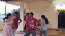 a group of people are dancing on a porch and one man is wearing a red shirt that says ' avengers '