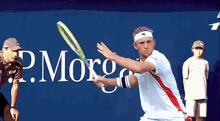 a tennis player is swinging a racket in front of a p. morga sign