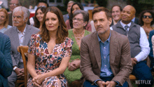 a man and a woman sit in front of a crowd with netflix written on the bottom