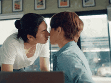 a man and a woman are kissing in front of a window in a restaurant .