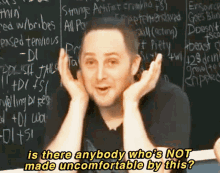 a man is standing in front of a blackboard with the words is there anybody who 's not made uncomfortable by this written on it