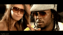 a man wearing sunglasses stands next to a woman wearing earrings