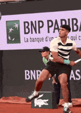 a man playing tennis in front of a bnp paribas ad