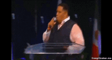 a man is standing at a podium holding a microphone .